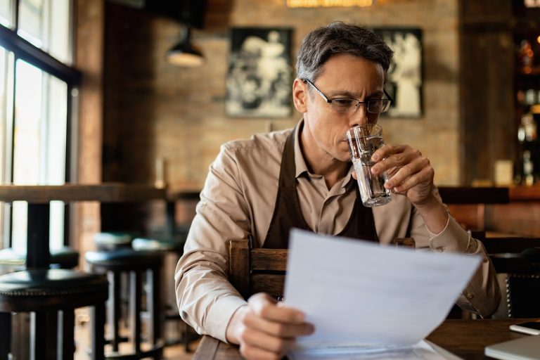 A restaurant owner revewing a pest control inspection report to ensure compliance with health and safety regualtions.