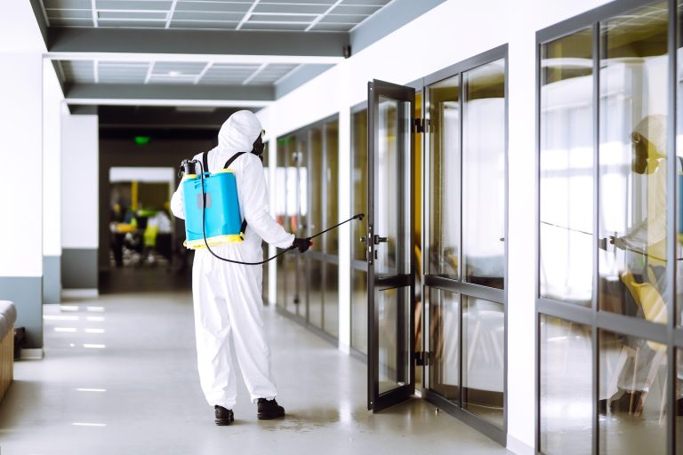 A pest control technician applying eco-friendly treatment in an office building to prevent insect infestations.